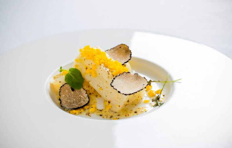 assiette blanche avec des rondelles de truffe un poireau vinaigrette et un oeuf mimosa