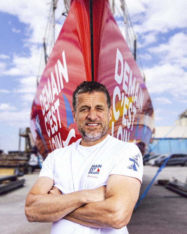 Nicolas Rougier pose devant son bateau rouge sur lequel est écrit Demain c'est loin 