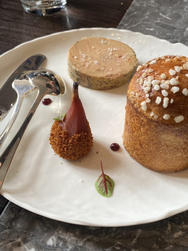 Assiette blanche avec brioche, rondelle de foie gras et poire