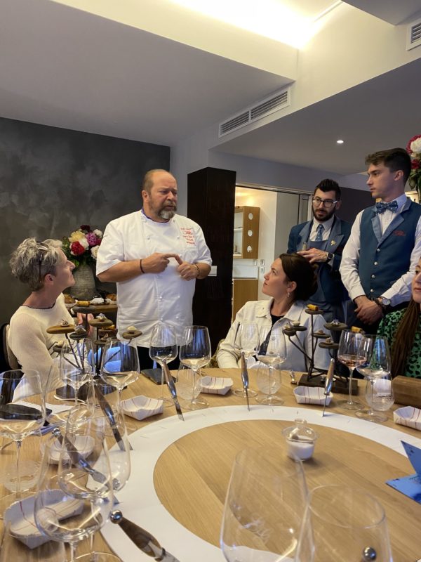 Le chef Gilles Goujon parle de sa cuisine avec plusieurs personnes autour de la table 