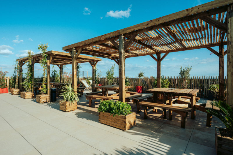 Terrasse avec table de bois couverte de pergolas de bois 