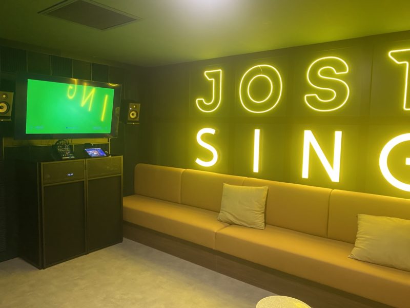 Pièce avec poste de télévision canapés en cuir beige et en néon jaune aux murs écrit Jost Sing