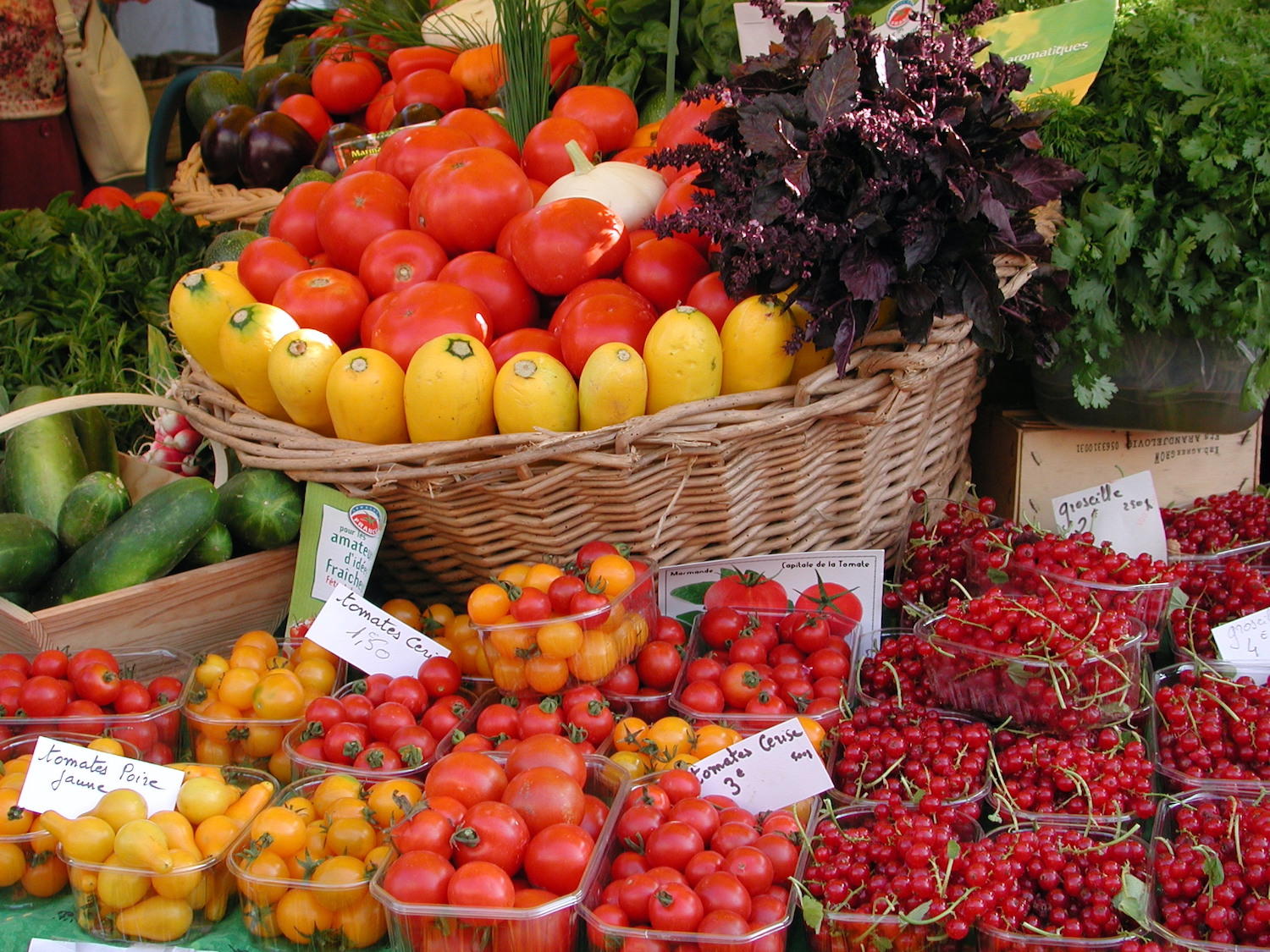 sur le marché corbeilles de fraises, de tomates de courgettes tout est rouge et jaune